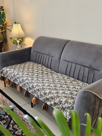 Gray sofa with a patterned cushion and decorative items on a shelf.
