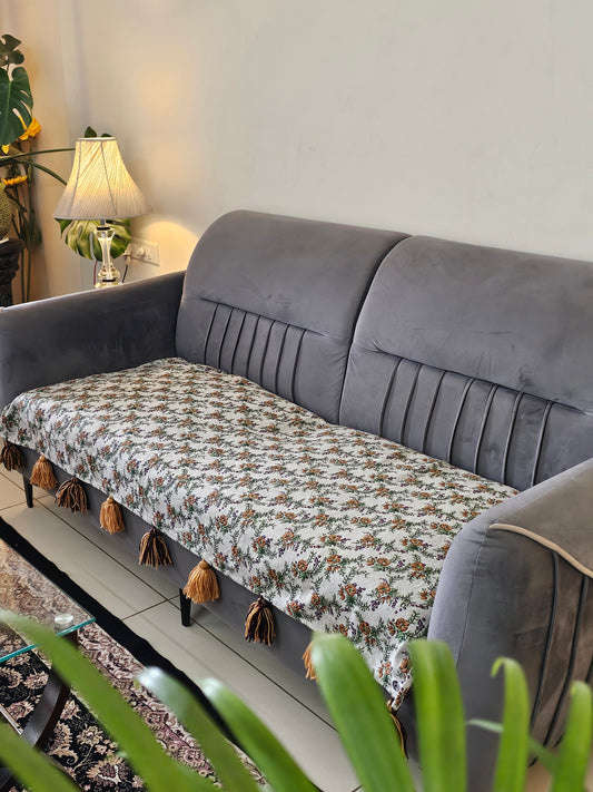 Gray sofa with a patterned cushion and decorative items on a shelf.
