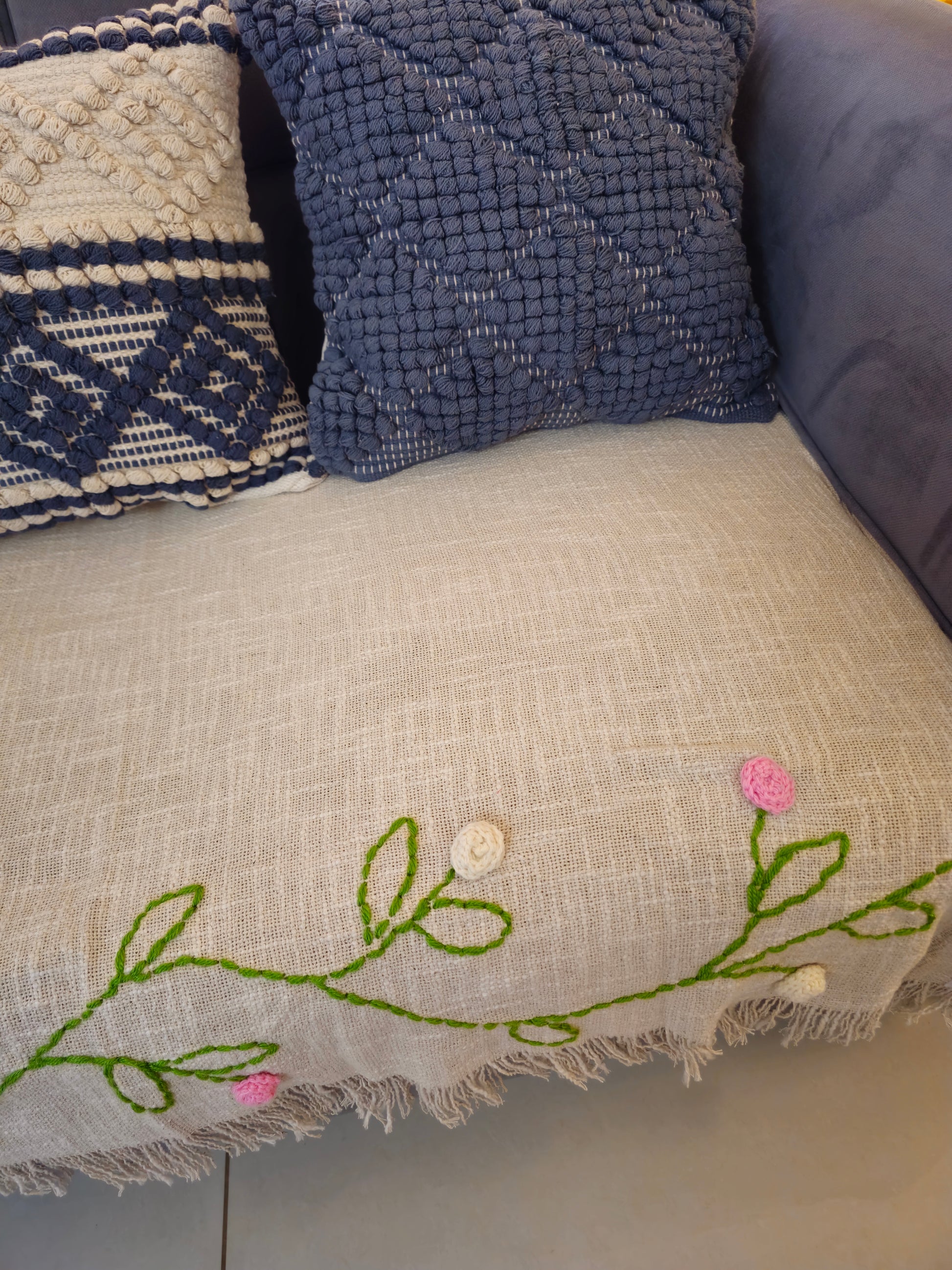 Close-up of a textured pillow with floral embroidery on a sofa.