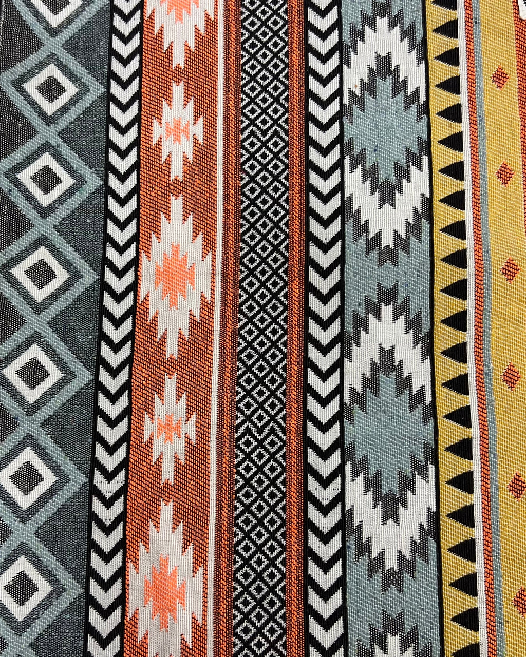 Geometric bohemian jacquard cotton placemat featuring a woven Aztec stripe and diamond pattern in rust orange, mustard, and slate gray.