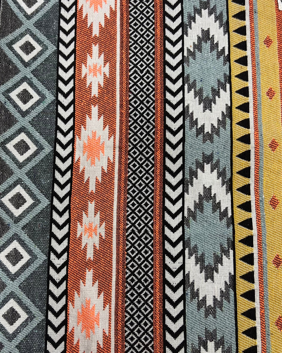 Geometric bohemian jacquard cotton placemat featuring a woven Aztec stripe and diamond pattern in rust orange, mustard, and slate gray.