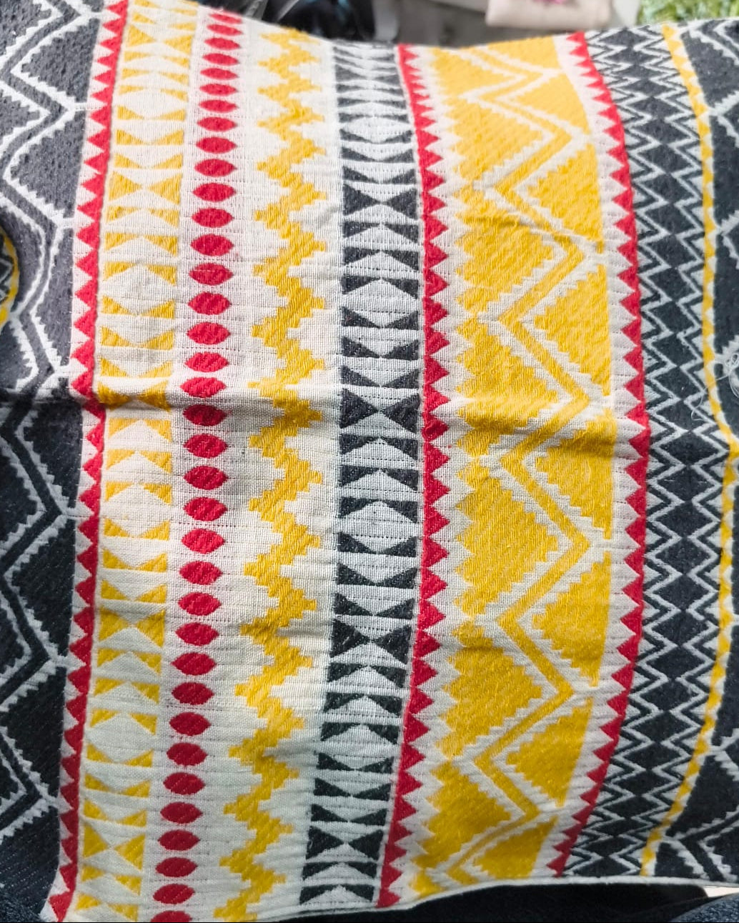 Square cream cotton cushion cover featuring a woven geometric jacquard pattern with yellow, red, and charcoal grey stripes and chevrons.