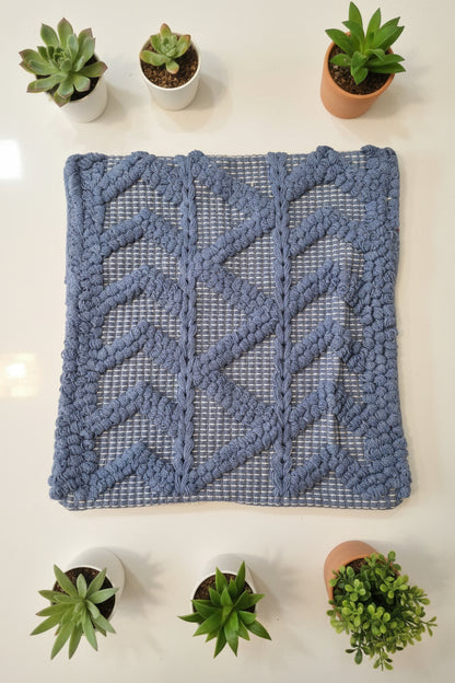 Blue textured rug on a white surface with a person wearing red pants partially visible.