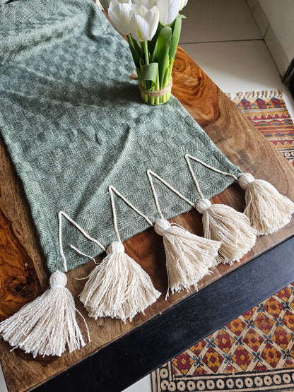 Decorative tassels on a wooden surface with a green towel and white flowers.