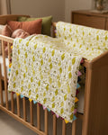 Fabric with a pattern of yellow leaves on a white background, placed on a textured dark fabric surface.