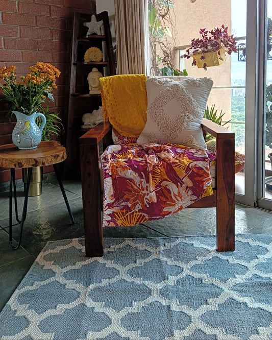 Colorful chair with a patterned cushion in a room with a rug, table, and window.