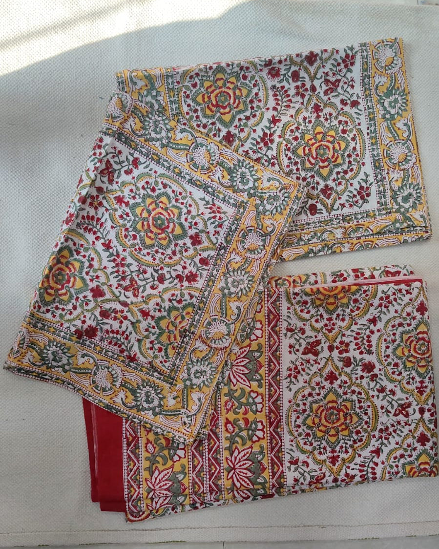 Folded 100x108 inch king size cotton bedsheet and matching pillow covers featuring a traditional red, yellow, and green handblock floral print.