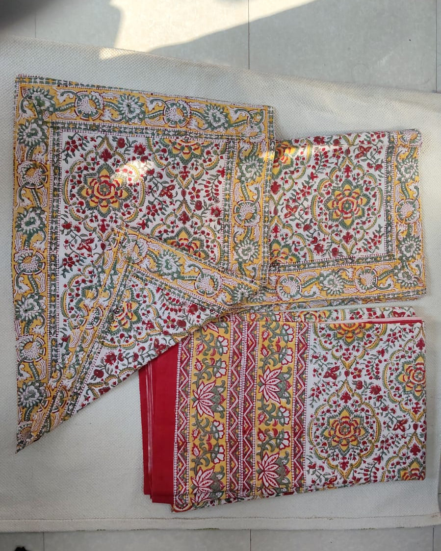 Folded 100x108 inch king size cotton bedsheet and matching pillow covers featuring a traditional red, yellow, and green handblock floral print.