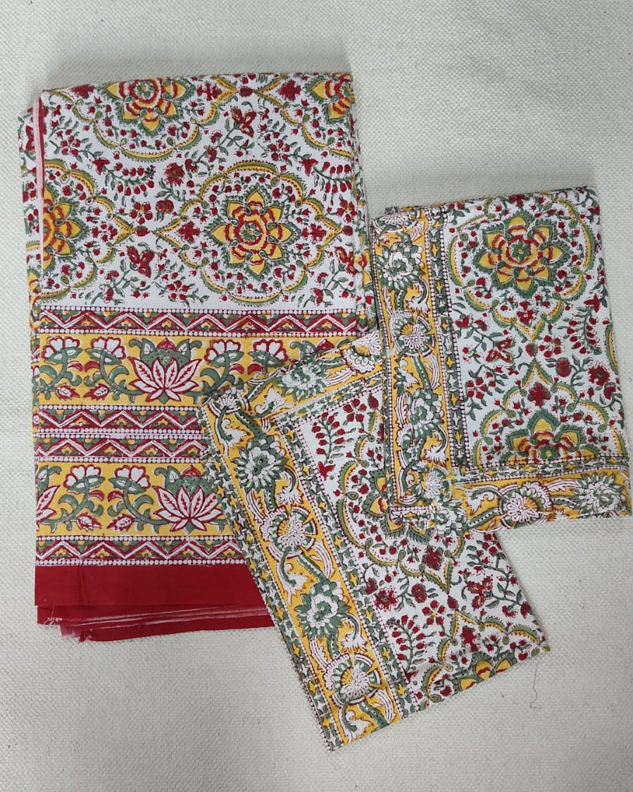 Folded 100x108 inch king size cotton bedsheet and matching pillow covers featuring a traditional red, yellow, and green handblock floral print.