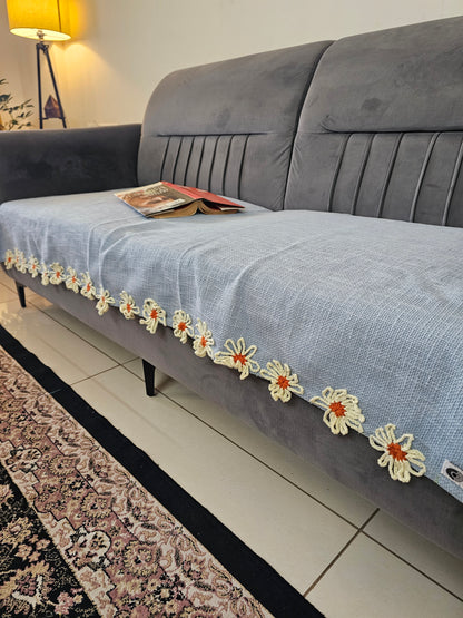 Gray suit with floral embroidery on a hanger against a tiled wall.