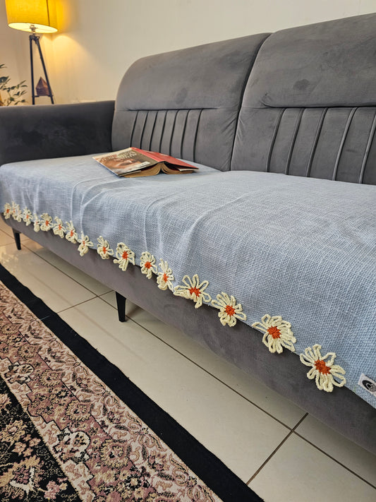 Gray suit with floral embroidery on a hanger against a tiled wall.