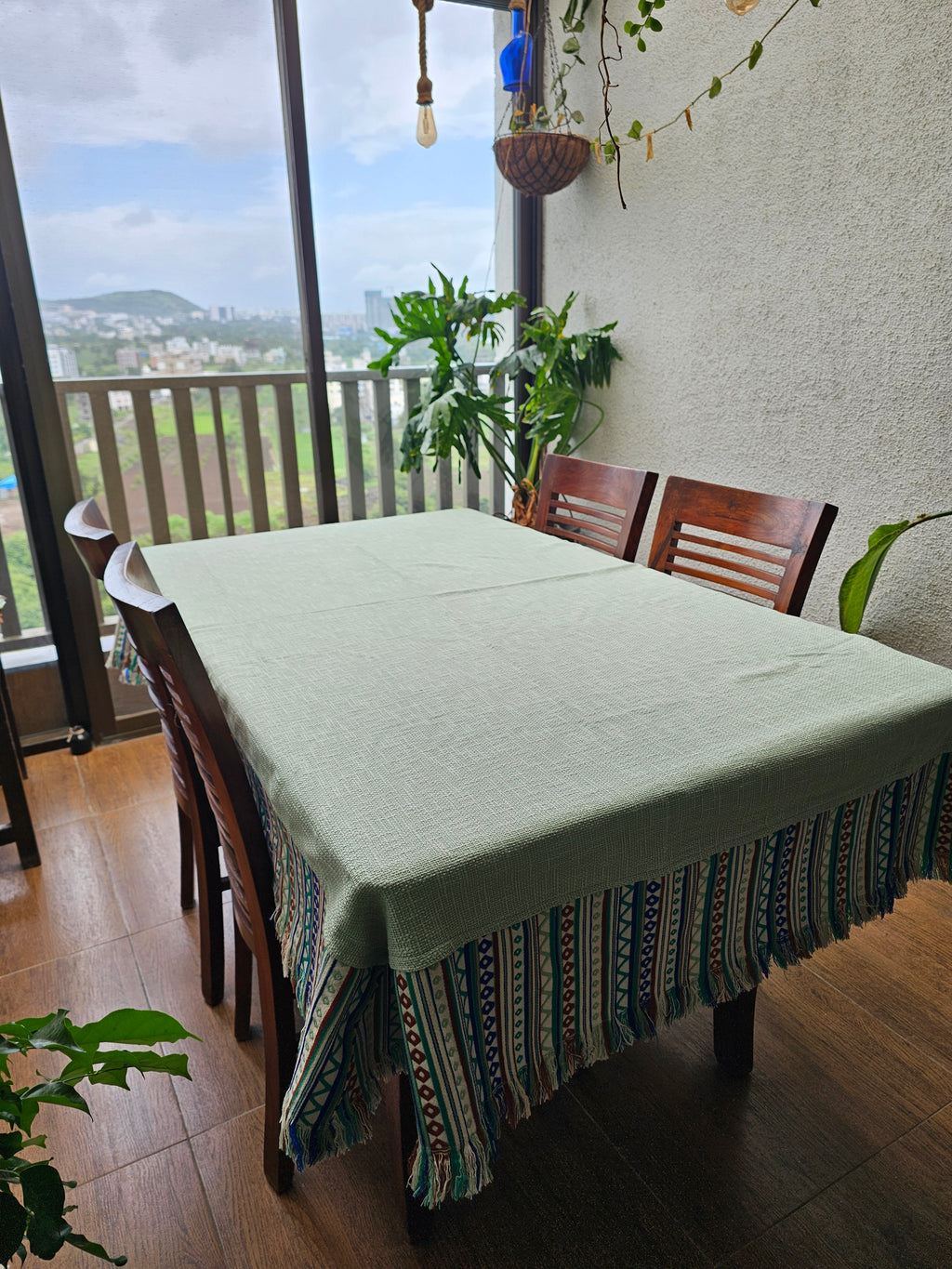 Dining table with a white tablecloth and decorative chair in a room with large windows.