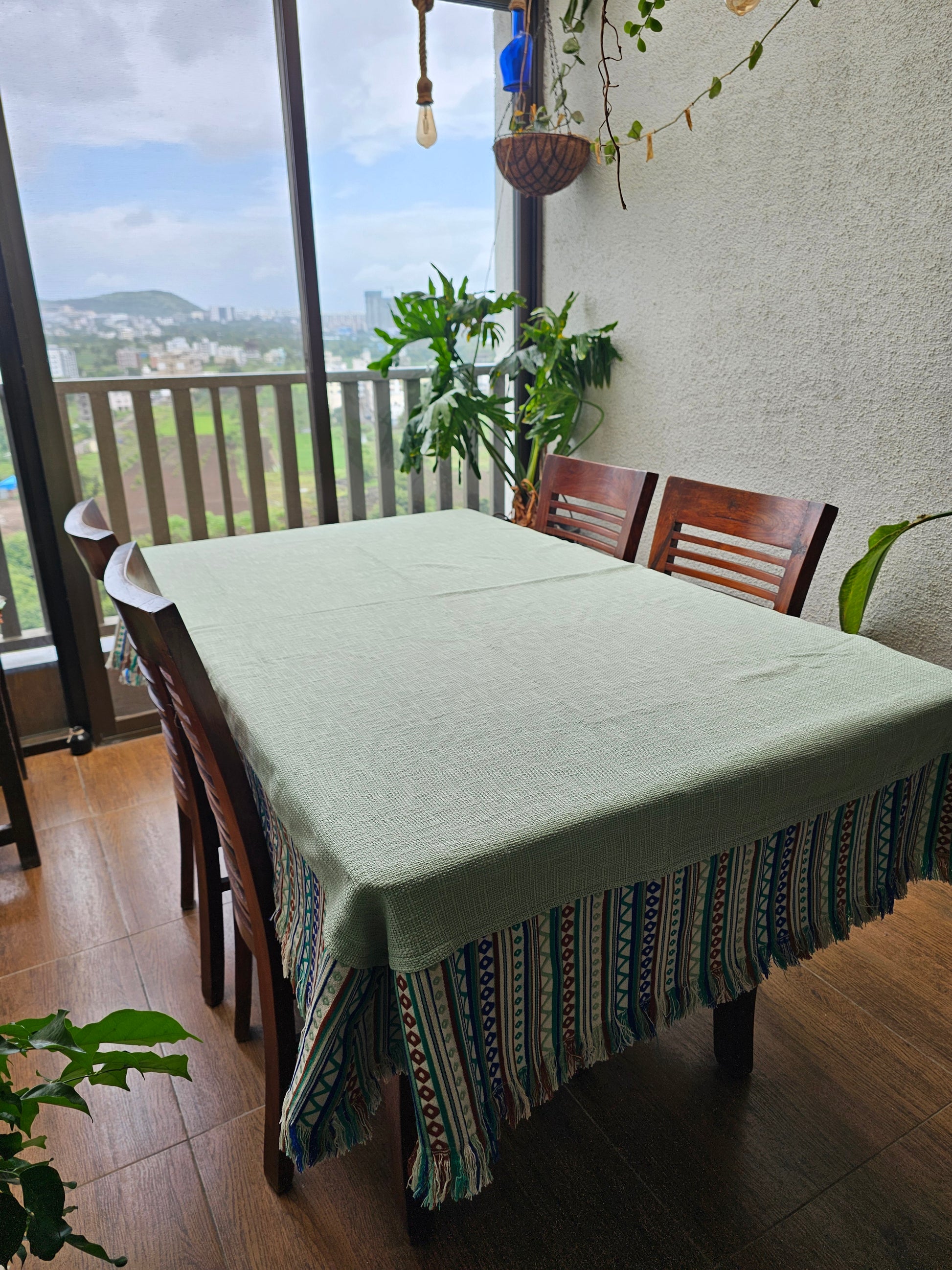 Dining table with a white tablecloth and decorative chair in a room with large windows.
