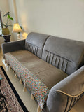 Gray sofa with a colorful patterned cushion on a white wall background