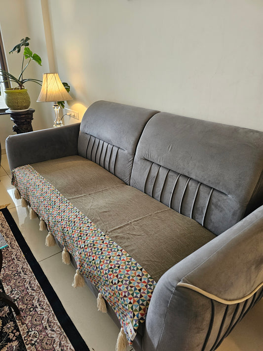 Gray sofa with a colorful patterned cushion on a white wall background