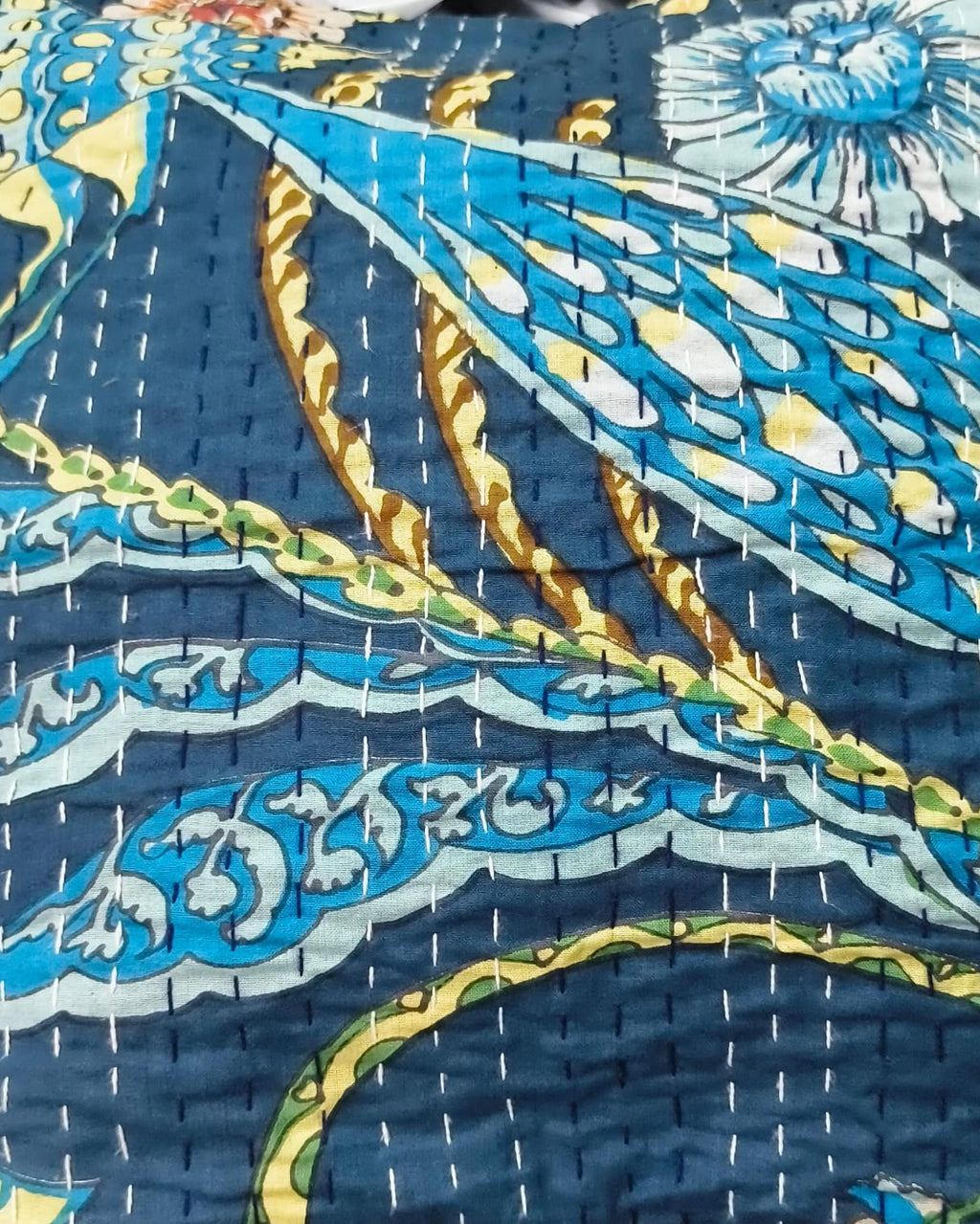Indigo blue cotton cushion cover featuring traditional hand-stitched kantha running lines and vibrant blue and yellow floral motifs.