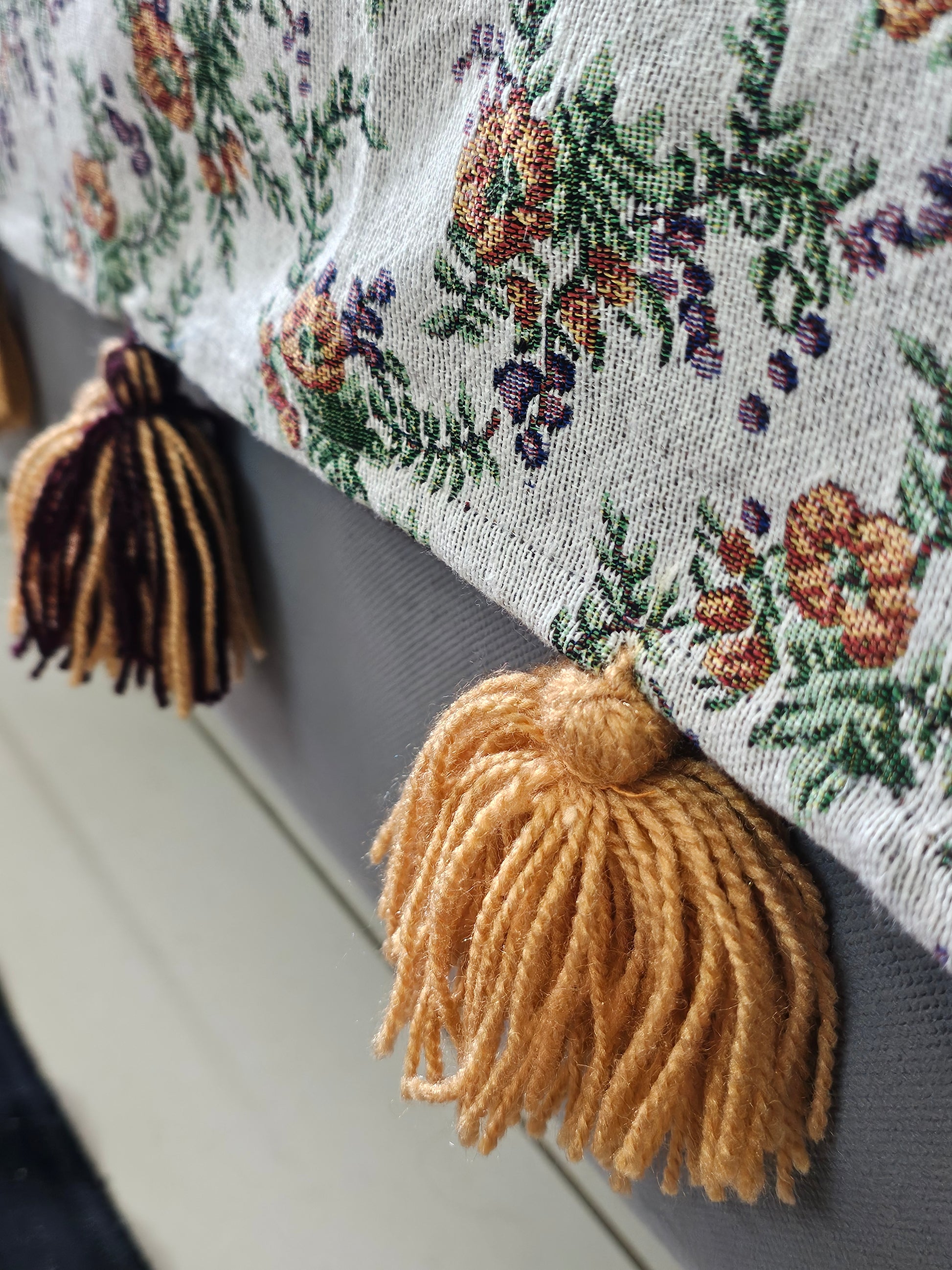 Close-up of a decorative fabric with floral patterns and tassels.