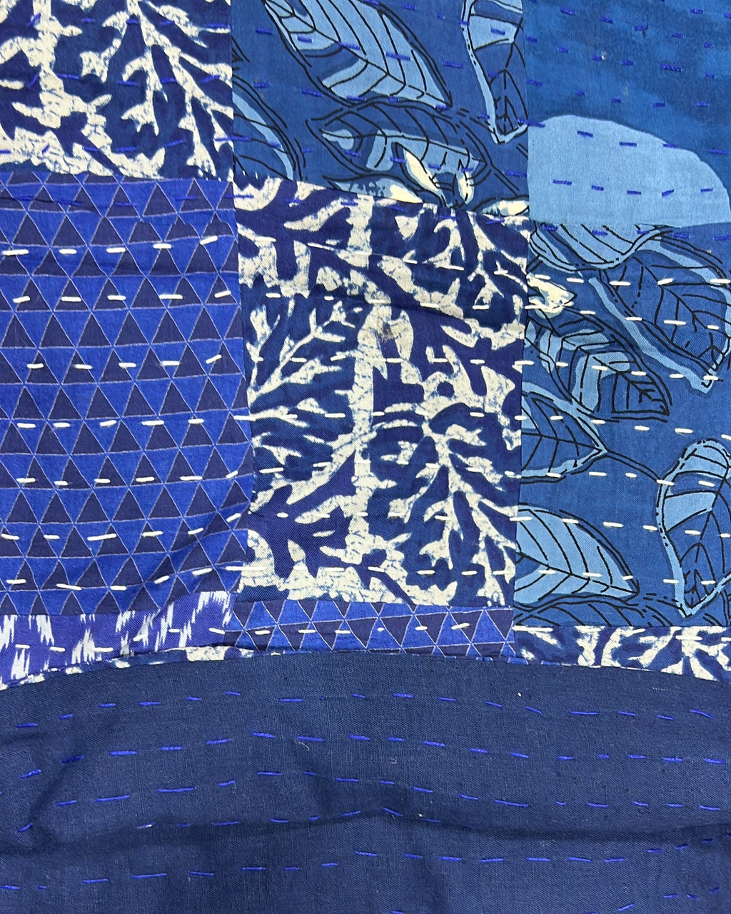 Indigo patchwork kantha cotton quilt featuring an intricate mix of deep blue block-printed geometric and botanical panels with traditional hand-stitching.