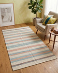 Close-up of an ivory handwoven cotton tufted rug featuring chunky alternating blue and peach tufted knots and delicate blue side stripes.