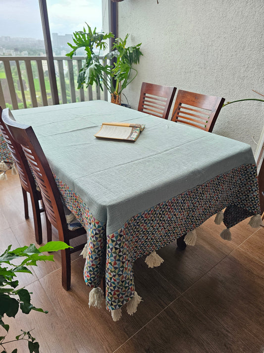 Dining table with chairs and a plant in a room with a window.