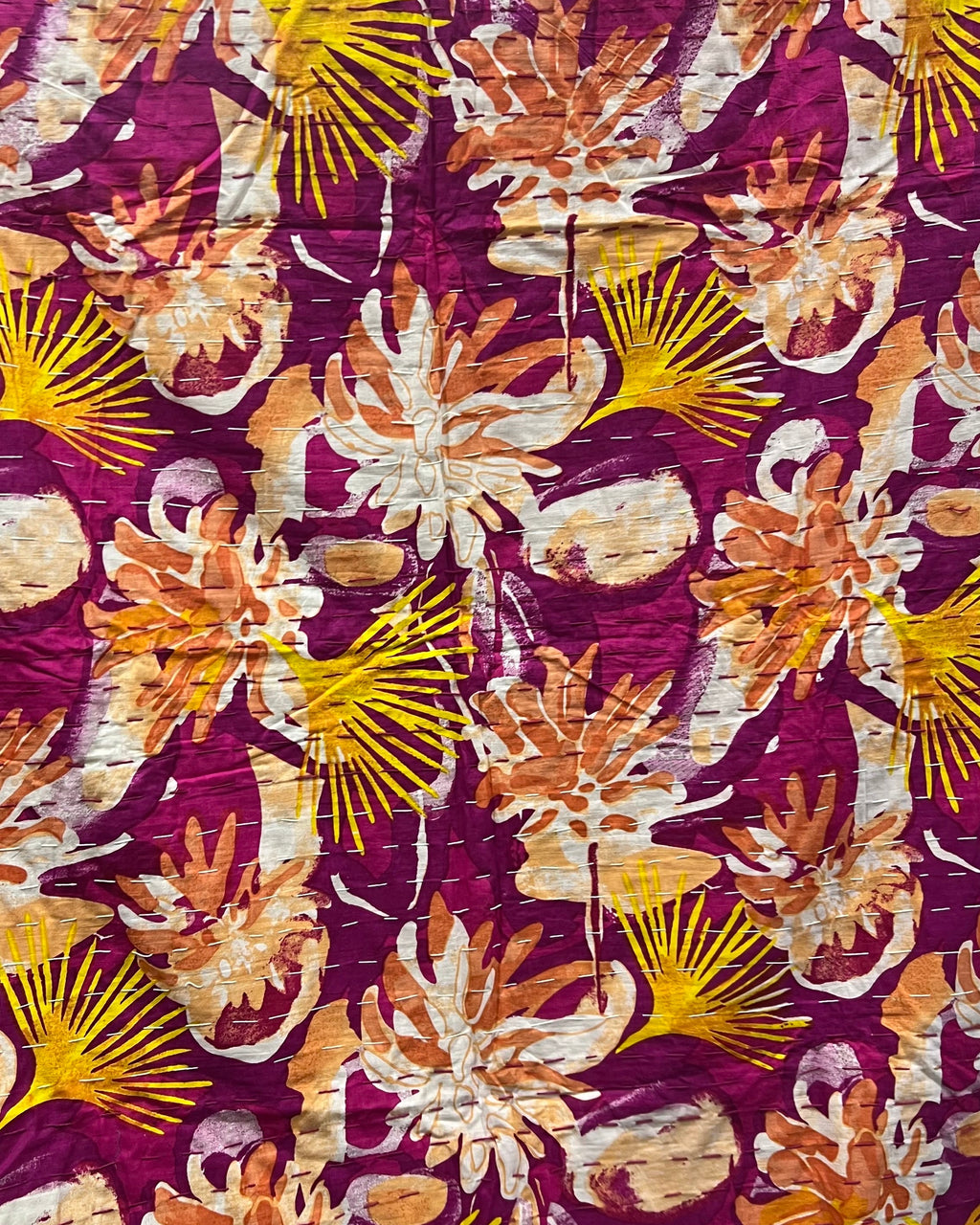 Magenta and mustard floral cotton kantha table cover featuring traditional running hand-stitching and a reversible solid yellow backing in a dining setup.