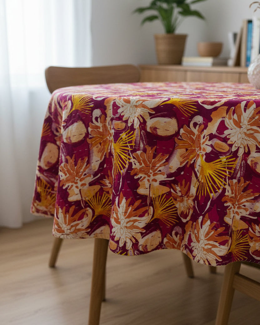 Magenta and mustard floral cotton kantha table cover featuring traditional running hand-stitching and a reversible solid yellow backing in a dining setup.