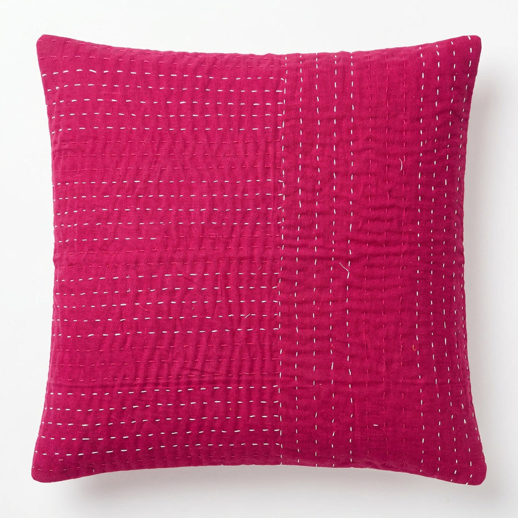Square magenta pink cotton cushion cover with white hand-stitched Kantha running embroidery laid flat on a light floor surface.