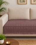Mauve purple handwoven cotton wool sofa throw cover with off-white dashed horizontal lines and matching fringe draped over a cream sofa.
