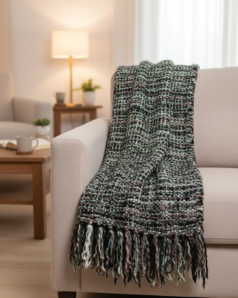 Mint green, blush pink, and charcoal black handwoven chunky woolen sofa throw blanket featuring a textured tweed basketweave and twisted fringe.