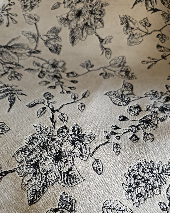 Rectangular off-white cotton placemat featuring a detailed black line-art floral botanical print laid flat.