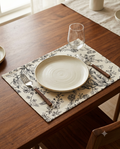 Rectangular off-white cotton placemat featuring a detailed black line-art floral botanical print laid flat.