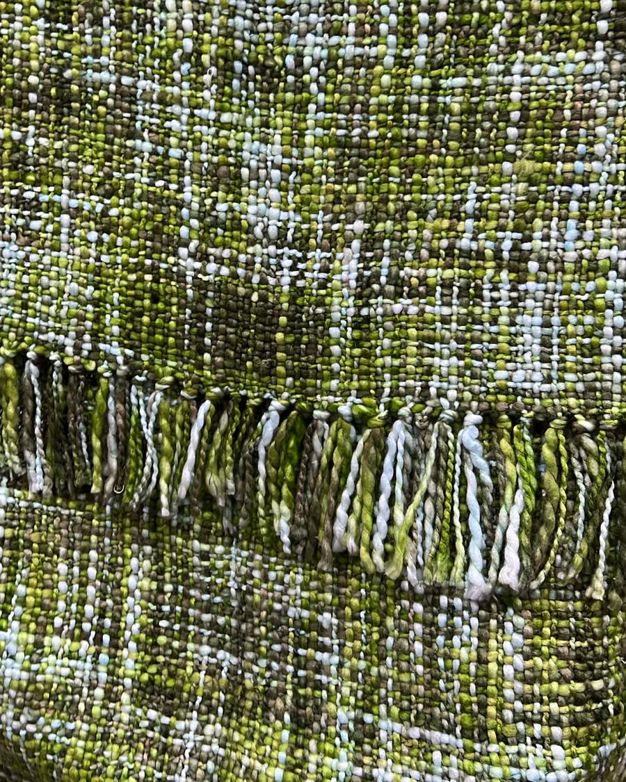 Moss olive and forest green handwoven chunky woolen sofa throw blanket featuring a textured tweed basketweave and twisted fringe tassels.