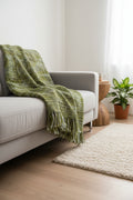 Moss olive and forest green handwoven chunky woolen sofa throw blanket featuring a textured tweed basketweave and twisted fringe tassels.