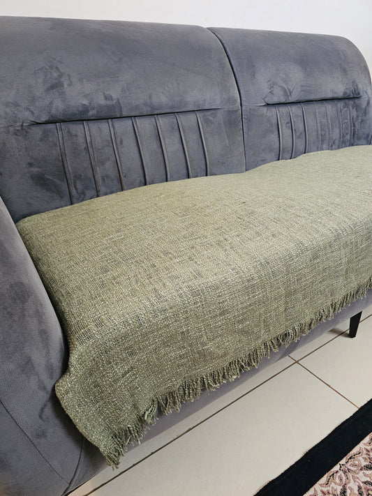 Green textured blanket draped over a gray sofa