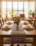 Multicolor Aztec Jacquard cotton dining table runner featuring vibrant geometric tribal bands and alternating magenta and off-white woolen hanging tassels, with Vasaca brand labels.