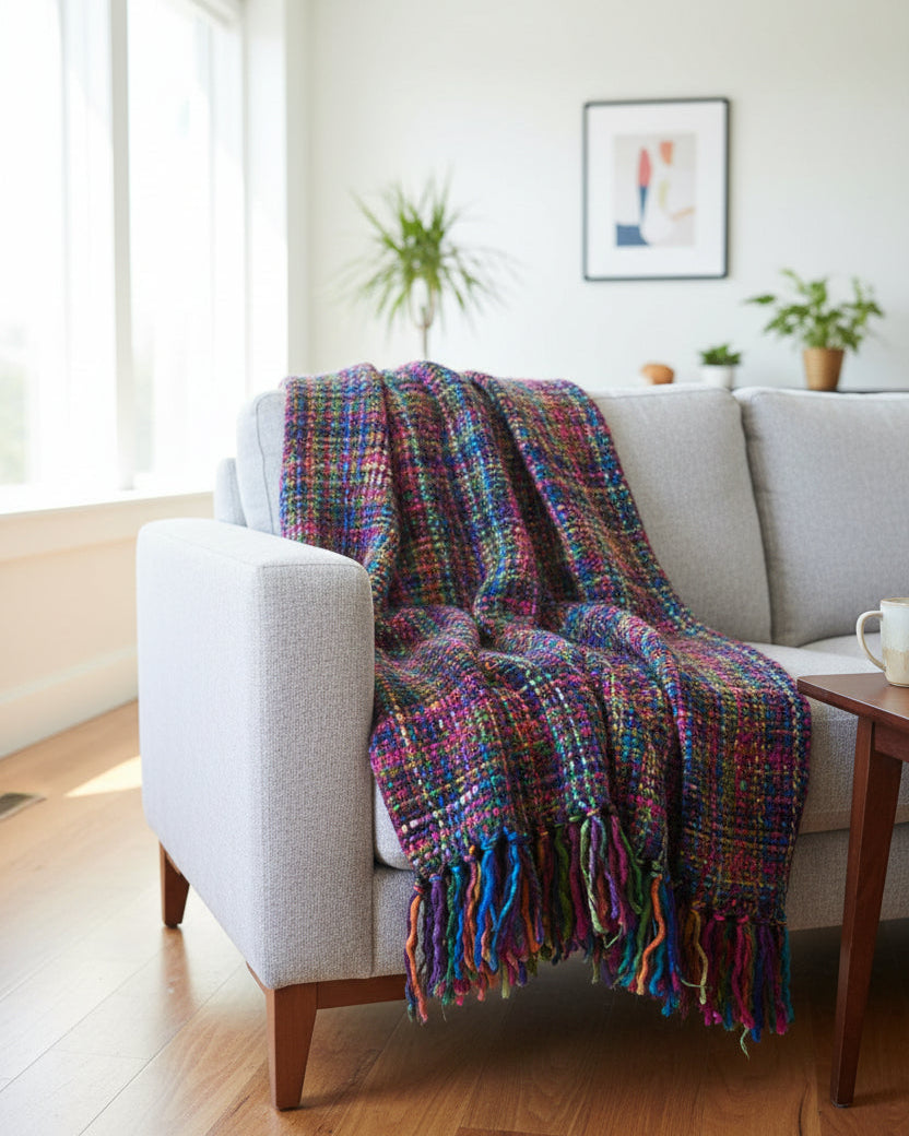 Multicolor handwoven chunky woolen sofa throw blanket featuring a rich tweed basketweave in magenta, blue, green, and purple jewel tones with plush fringe.