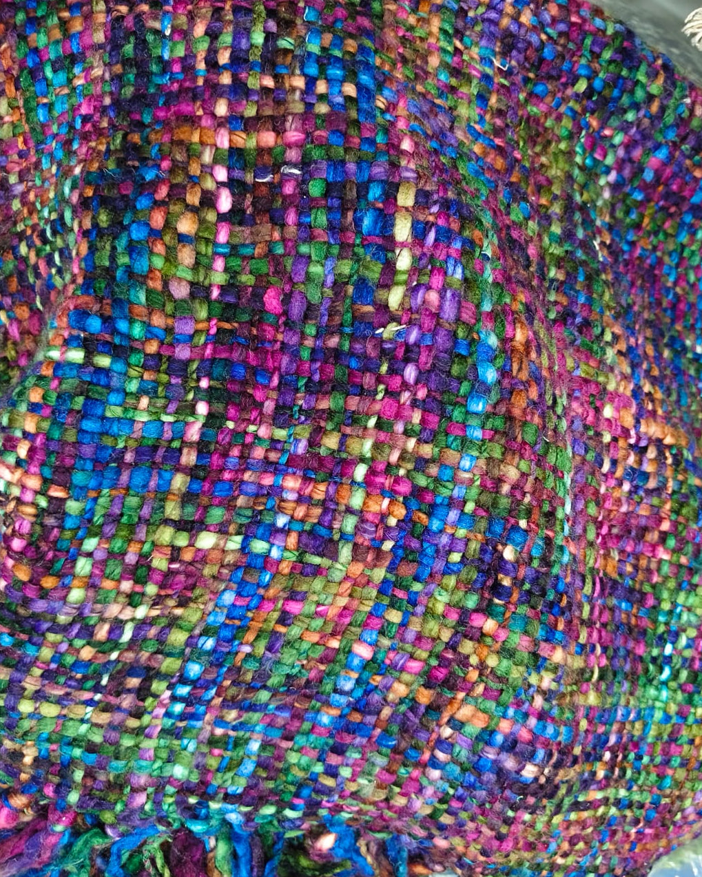 Multicolor handwoven chunky woolen sofa throw blanket featuring a rich tweed basketweave in magenta, blue, green, and purple jewel tones with plush fringe.