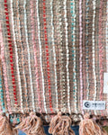 Multicolor stripe cotton handloom table runner featuring vertical woven lines in red, pink, and turquoise with chunky yarn tassels, and Vasaca brand labels.