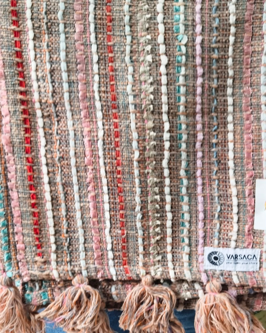 Multicolor stripe cotton handloom table runner featuring vertical woven lines in red, pink, and turquoise with chunky yarn tassels, and Vasaca brand labels.