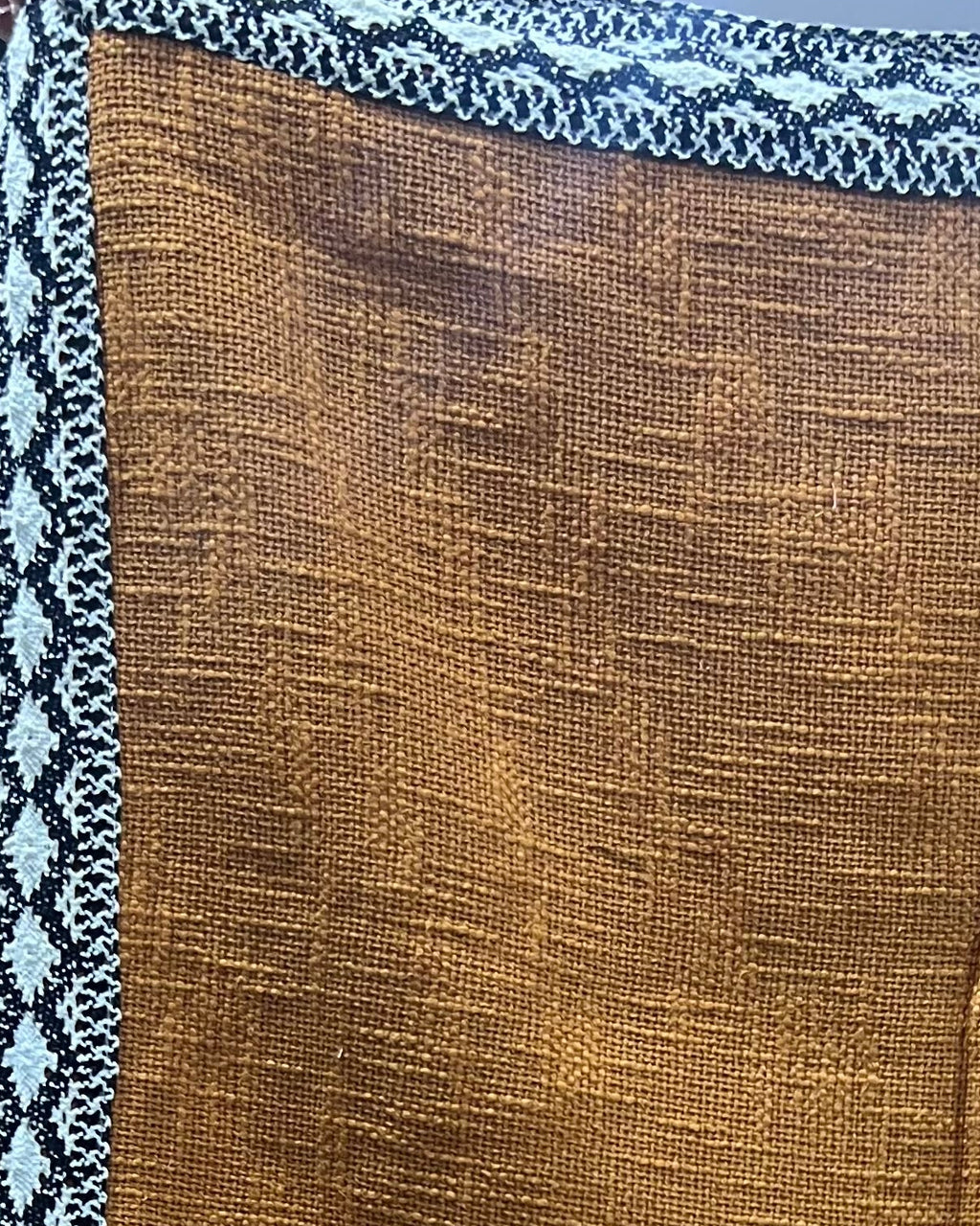 Solid mustard yellow handloom cotton table cover framed by a striking black and white geometric patterned border.