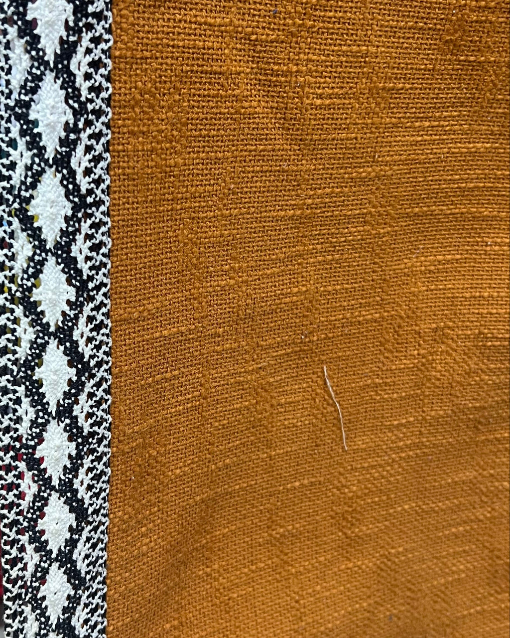 Solid mustard yellow handloom cotton table cover framed by a striking black and white geometric patterned border.