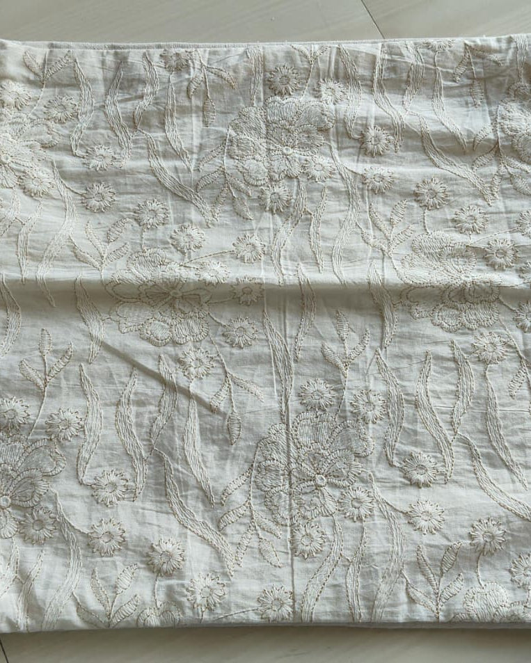 Square off-white cotton cushion cover with all-over hand-embroidered floral vine threadwork displayed flat.