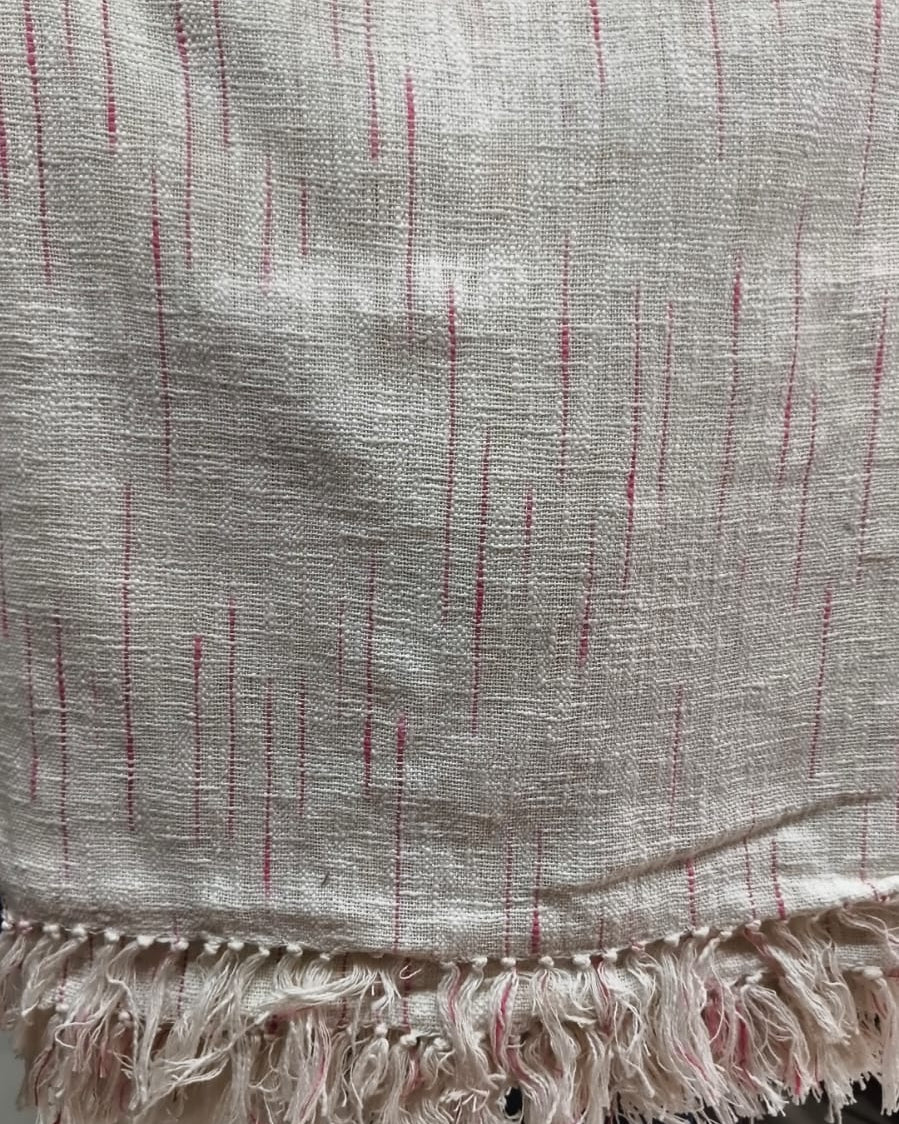 Natural off-white handloom slub cotton king size bed cover featuring subtle pink accent stripes and handcrafted fringe tassels.