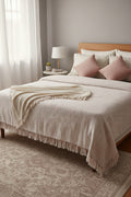 Natural off-white handloom slub cotton king size bed cover featuring subtle pink accent stripes and handcrafted fringe tassels.