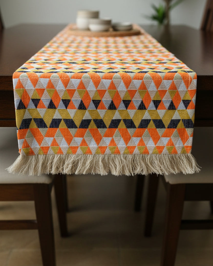 Orange geometric Jacquard cotton dining table runner featuring a vibrant triangle mosaic pattern and a textured fringe hem, with Vasaca brand labels.