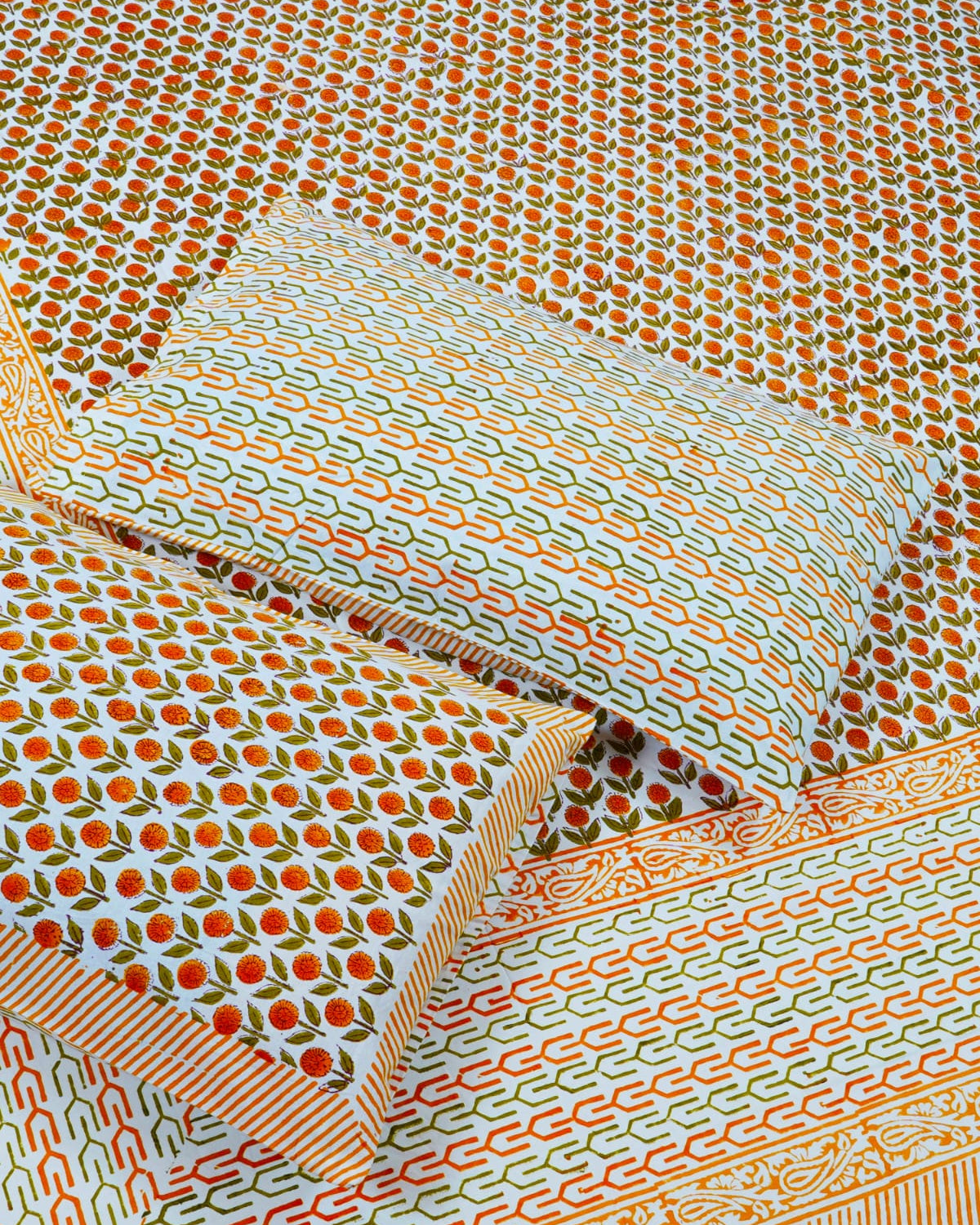 100x108 inch king size cotton bedsheet and matching pillow covers styled with a traditional orange and green floral bud handblock print.