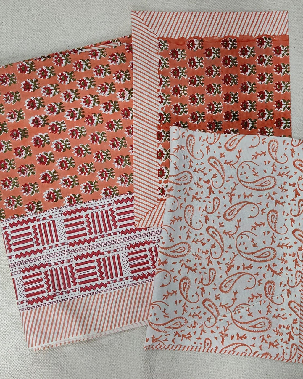 Folded 100x108 inch king size cotton bedsheet and matching pillow covers featuring a traditional orange and white handblock floral and paisley print.