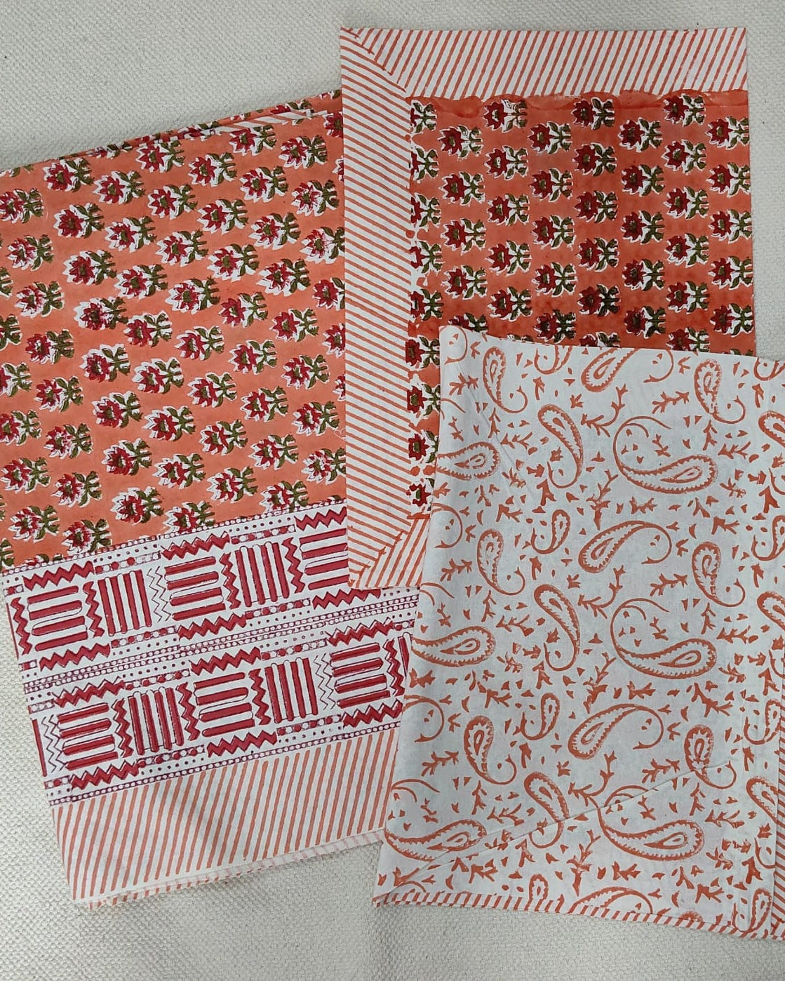 Folded 100x108 inch king size cotton bedsheet and matching pillow covers featuring a traditional orange and white handblock floral and paisley print.