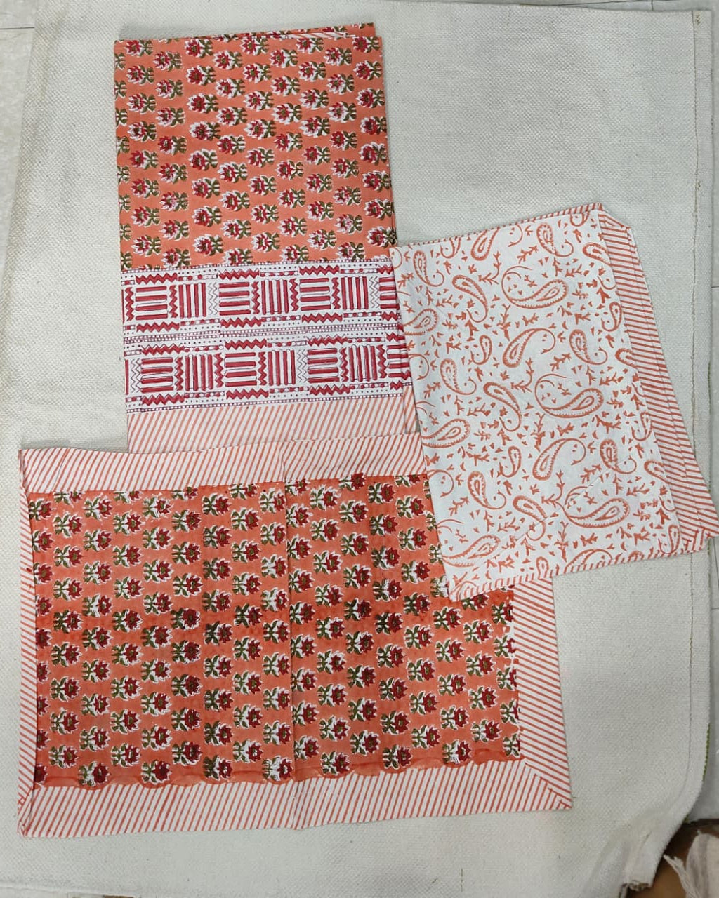 Folded 100x108 inch king size cotton bedsheet and matching pillow covers featuring a traditional orange and white handblock floral and paisley print.