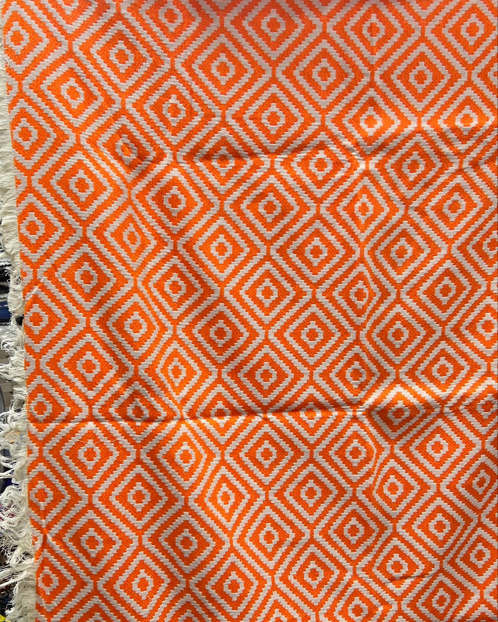 Orange and white geometric diamond pattern handloom cotton table cover featuring decorative fringe tassels along the edge.
